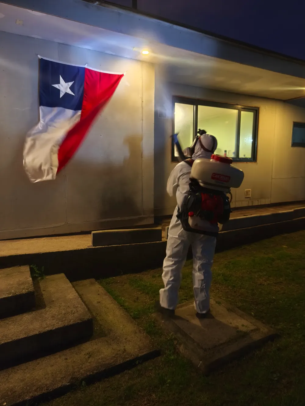 Fumigación nocturna de instalaciones junto a la bandera chilena