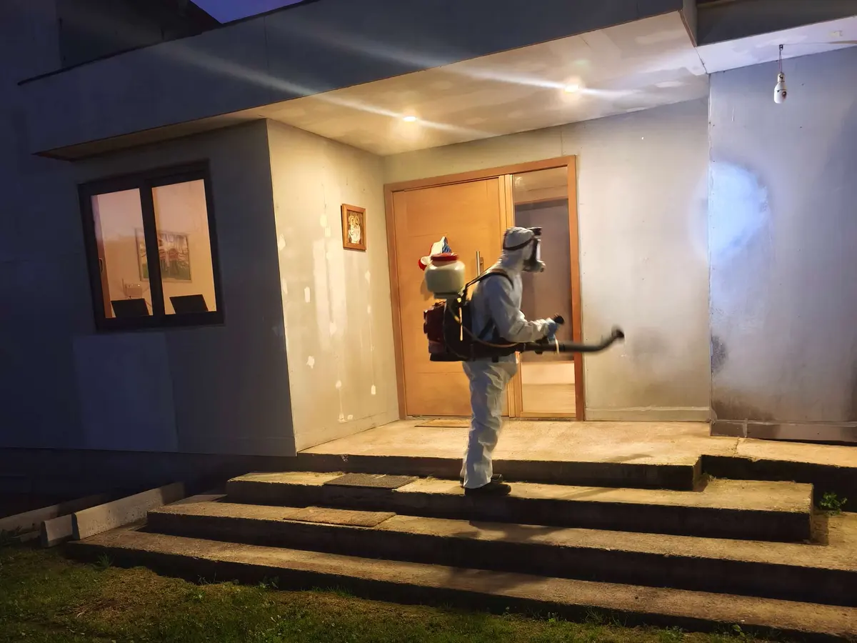 Técnico de VIS con traje de protección aplicando en la entrada de una casa: servicio a domicilio en Peñaflor